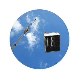 An air conditioning unit lifted by crane against a blue sky