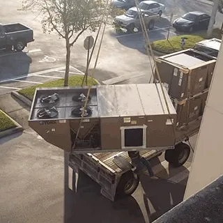 A rooftop unit lifted by crane from a truck